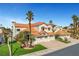 A two-story home has a terracotta tile roof and well manicured lawn with palm trees and three garage doors at 8132 Bay Harbor Dr, Las Vegas, NV 89128