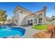 A bright, white two-story home with a red tile roof sits next to a backyard pool and green space at 8132 Bay Harbor Dr, Las Vegas, NV 89128