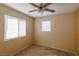 Neutral bedroom with two windows, a ceiling fan, and tan carpet at 9849 Ridge Hill Ave, Las Vegas, NV 89147