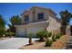 Two-story home featuring a three-car garage, desert landscaping, and tile roof at 10417 Niagara Falls Ln, Las Vegas, NV 89144