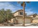 Attractive two-story home with a beige exterior, a palm tree, and a three-car garage at 1684 Flores Ln, Henderson, NV 89012