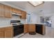 Functional kitchen featuring wood cabinets, black appliances, and a breakfast bar at 1813 Villa Vista Way, Las Vegas, NV 89128
