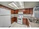 Galley kitchen features wood cabinets, white appliances, tile countertops, and light laminate flooring at 3411 Sunfish Dr # B, Henderson, NV 89014