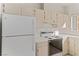 A close up of the kitchen featuring white appliances, light cabinets, and tile countertops at 3426 Dry Gulch Dr, Laughlin, NV 89029