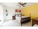 Comfortable bedroom with neutral carpet, a bed, and a vibrant yellow accent wall at 3949 S Torrey Pines Dr, Las Vegas, NV 89103