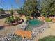A backyard pond and waterfall feature with desert landscaping and greenery at 4680 Suntree Ct, Pahrump, NV 89061