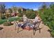 Backyard fire pit area with chairs surrounded by lush plants and lawn at 4680 Suntree Ct, Pahrump, NV 89061