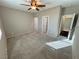 A large room with neutral carpet, ceiling fan, and multiple doorways at 4680 Suntree Ct, Pahrump, NV 89061