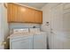 Functional laundry area with wooden cabinets above the washer and dryer and access to the back at 5419 Sharpei Ct, Las Vegas, NV 89131