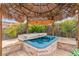 Secluded hot tub area with tiki-style palapa, stone accents, and lush landscaping for privacy at 6405 Break Point Ave, Las Vegas, NV 89130