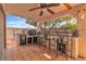 Stylish outdoor bar area with tile flooring, ceiling fan, built-in grill, and seating for entertaining at 6405 Break Point Ave, Las Vegas, NV 89130