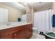 Well-lit bathroom with a wood vanity, a large mirror, and a shower-tub combination with a white curtain at 6476 Little Harbor Ct, Las Vegas, NV 89141