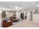 Open living room with carpet, leather couches, ceiling fan, and a glimpse of other rooms in the home at 6476 Little Harbor Ct, Las Vegas, NV 89141
