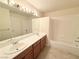 Bathroom features a double sink vanity with wood cabinets and a tub with shower at 6625 Gossamer Fog Ave, Las Vegas, NV 89139