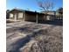 Exterior shot of a one story home with stucco and boarded up windows, plus a covered carport at 709 G St, Las Vegas, NV 89106