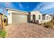 Charming single-story home with a brick driveway, two-car garage, stone accents, and arched entryway at 76 Tatahatso Point St, Henderson, NV 89011