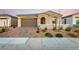 Charming single-story home with a brick driveway, two-car garage, stone accents, and arched entryway at 76 Tatahatso Point St, Henderson, NV 89011