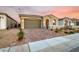 Charming single-story home featuring a brick driveway, two-car garage, stone accents, and desert landscaping at 76 Tatahatso Point St, Henderson, NV 89011