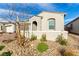Charming single-story home with a desert landscape, two-car garage, stone accents, and arched entryway at 76 Tatahatso Point St, Henderson, NV 89011