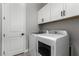 Bright laundry room with white cabinets and modern, front-loading washer and dryer at 76 Tatahatso Point St, Henderson, NV 89011