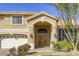 Inviting front entrance with double doors, a three-car garage, and lush landscaping at 7641 Jacaranda Bay St, Las Vegas, NV 89139