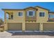 Three-car garage with exterior featuring a mix of light-brown stucco and blue shutter accents at 8490 Classique Ave # 101, Las Vegas, NV 89178