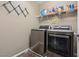 Well-organized laundry room featuring side by side washer and dryer with storage shelves stocked with cleaning supplies at 922 Harbor Ave, Henderson, NV 89002