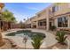 Lovely backyard pool with covered patio, desert landscaping, and second story balcony at 10748 Aldrovandi Dr, Las Vegas, NV 89141