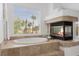 Beautiful bathroom featuring a luxurious tub, fireplace and a large window for natural light at 10748 Aldrovandi Dr, Las Vegas, NV 89141