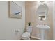 Powder room featuring pedestal sink, toilet, decorative mirror and contemporary lighting at 10748 Aldrovandi Dr, Las Vegas, NV 89141