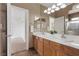 Bright bathroom with double sinks, wood cabinets, and a large mirror at 10748 Aldrovandi Dr, Las Vegas, NV 89141