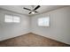 This carpeted bedroom has paneled walls, a ceiling fan, and natural light from two windows at 1113 Date St, Las Vegas, NV 89108