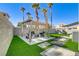Inviting backyard featuring a covered patio, artificial grass, and mature palm trees at 139 Serenade Ct, Henderson, NV 89074