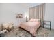 Stylish bedroom featuring a floral rug, comfortable chair, neutral curtain and a cozy pink patterned quilt at 148 Tre Pietre St, Henderson, NV 89011