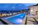 A modern backyard at twilight showcases a stunning pool and spa, complemented by an outdoor kitchen for luxurious living at 148 Tre Pietre St, Henderson, NV 89011