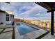 A modern backyard features a sleek pool and spa, enhanced by beautiful stone tiling and artificial turf accents at 148 Tre Pietre St, Henderson, NV 89011