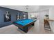 A stylish game room with a blue pool table, accent wall with artwork, and a view into the adjacent dining area at 1912 Calanda Ct, Las Vegas, NV 89102