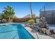 Sparkling pool featuring rock waterfall, palm trees, and manicured landscaping for a serene backyard oasis at 1912 Calanda Ct, Las Vegas, NV 89102