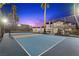 View of a well-maintained tennis court with a basketball hoop, framed by palm trees at 1912 Calanda Ct, Las Vegas, NV 89102