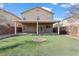 Expansive backyard featuring artificial turf, a covered patio, and a charming fire pit for outdoor entertaining at 2624 Courlan Dr, North Las Vegas, NV 89084