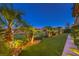 Night view of backyard showcasing professional landscaping with palm trees, green grass and path lighting at 2994 San Lorenzo Ct, Henderson, NV 89052