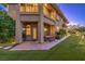 Back exterior view of home showing upper balcony, lower patio with dining set, and artificial turf at 2994 San Lorenzo Ct, Henderson, NV 89052