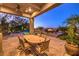 Expansive covered patio with dining table, ceiling fan, and comfortable lounge area overlooking the pool and fire pit at 2994 San Lorenzo Ct, Henderson, NV 89052