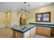 Well-lit kitchen featuring an island with a sink, wooden cabinets, and unique, decorative lighting at 3101 Margarita St, Pahrump, NV 89048