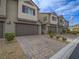 Exterior view of townhomes featuring brick-paved driveways, garages and desert landscaping at 3795 Canis Minor Ln # 5102, Henderson, NV 89052