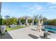 This backyard features a luxurious outdoor kitchen under a trellis, a fire pit, a pool with lounge chairs, and manicured landscaping at 4208 Lapis Ridge Ct, Las Vegas, NV 89135