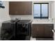Modern laundry room with front-load washer/dryer, ample cabinet space, and a sink for added convenience at 4208 Lapis Ridge Ct, Las Vegas, NV 89135