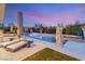 An elegant patio and pool area at dusk, with statues and comfortable outdoor furniture at 4208 Lapis Ridge Ct, Las Vegas, NV 89135