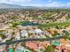 Scenic aerial view of a community showcasing lush landscaping and a nearby golf course with a tranquil pond and mountain views at 5205 Sandy Cactus Ln, Las Vegas, NV 89149
