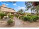 Lush backyard with a stone walkway, mature trees, manicured hedges, and a covered patio with ample seating at 5205 Sandy Cactus Ln, Las Vegas, NV 89149